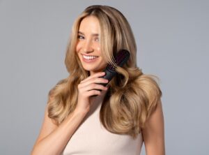 a woman holding a hair brush in her hand straightening brush