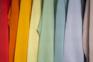 a bunch of different colored shirts hanging on a rack
