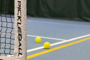 three tennis balls on a tennis court near a net pickleball